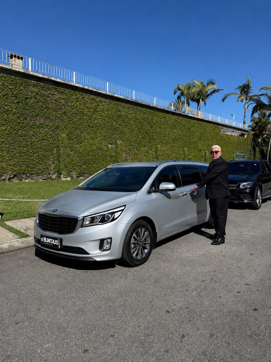 Chauffeur Blintaxi ao lado da Kia Carnival blindada