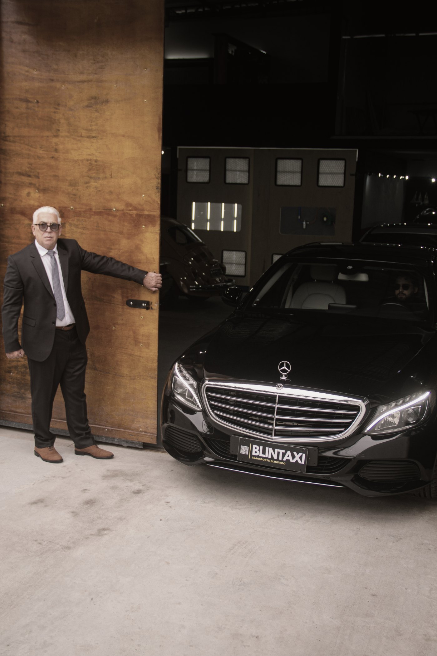 Chauffeur Blintaxi ao lado do veículo blindado, atendimento aeroportuário